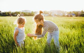 Little girls looking at insects in the green grass | Apexleadership